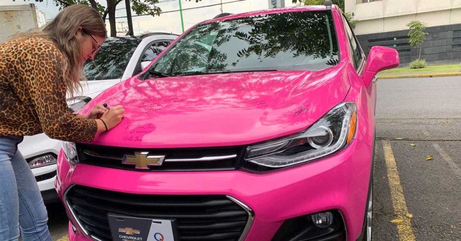 mujer firmando en carro rosado