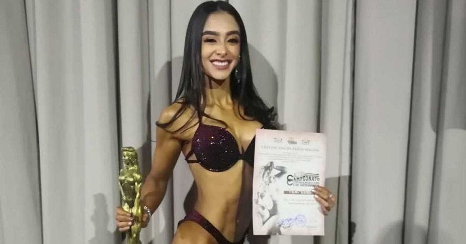 Mujer en vestido e baño y trofeo en mano