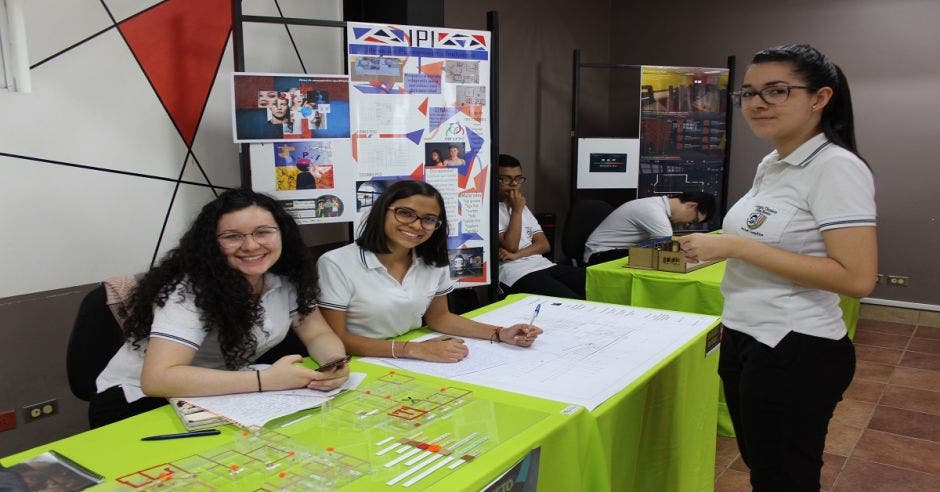 Tres estudiantes exhibiendo un proyecto