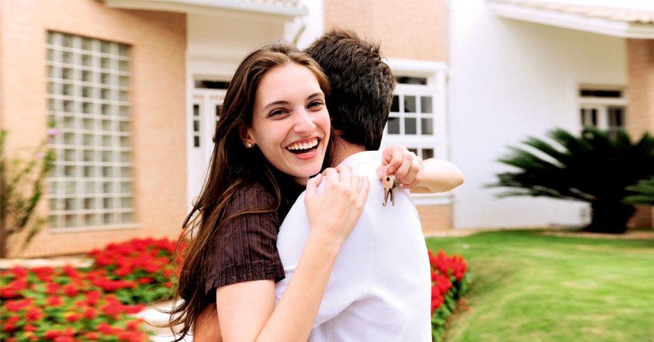 Dos jóvenes abrazados frente a una casa