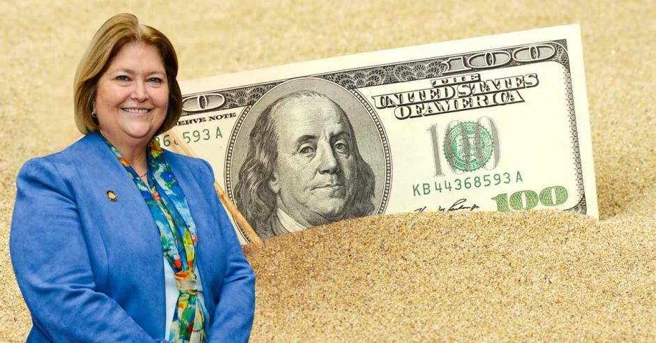 María Amalia Revelo, ministra de Turismo, posa junto a un billete de un dólar en la playa