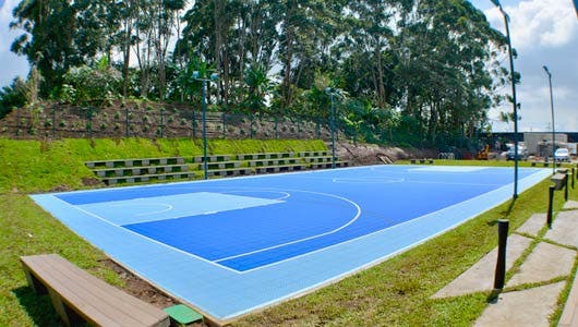 Una cancha de fútbol micro, pintada de color azul. Al fondo se ven unos árboles