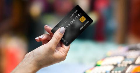 Una mano de mujer presentando una tarjeta de crédito de color negro.
