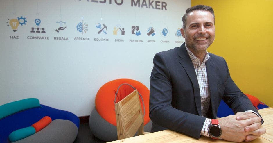 El gerente de traje sonriendo, sentado en una mesa de madera