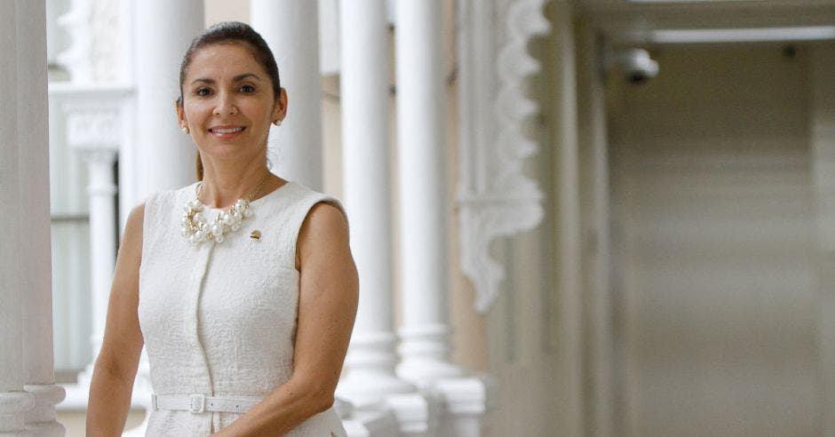 La diputada vestida de blanco en un fondo donde se ve una arquitectura de origen musulmán, ya que se trata del jardín moro del COngreso