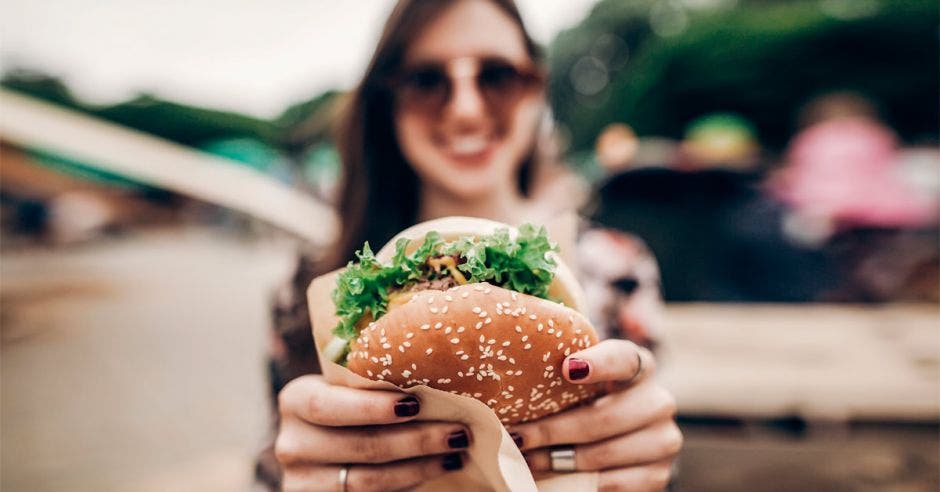 mujer mostrando una hamburguesa