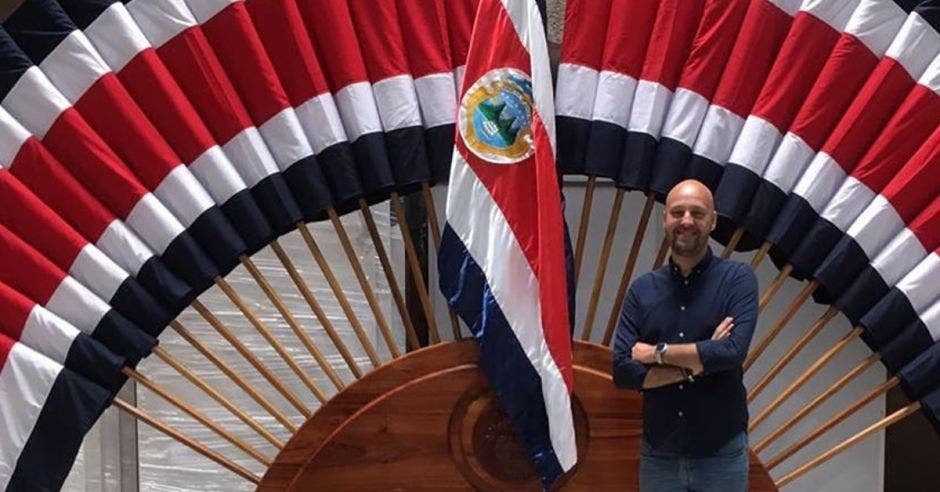 Federico Cartín posa frente a un pabellón nacional. En el fondo se ven un montón de banderas.