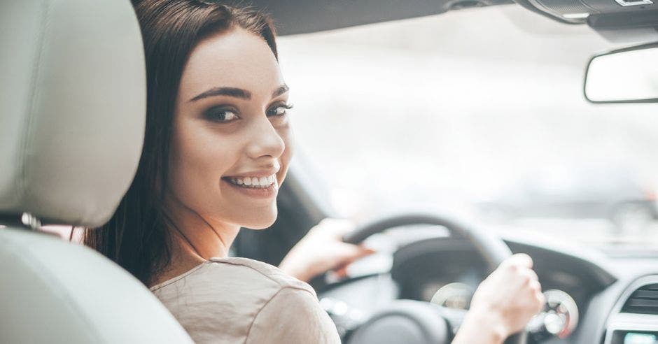 Un mujer sonriente conduce un automóvil