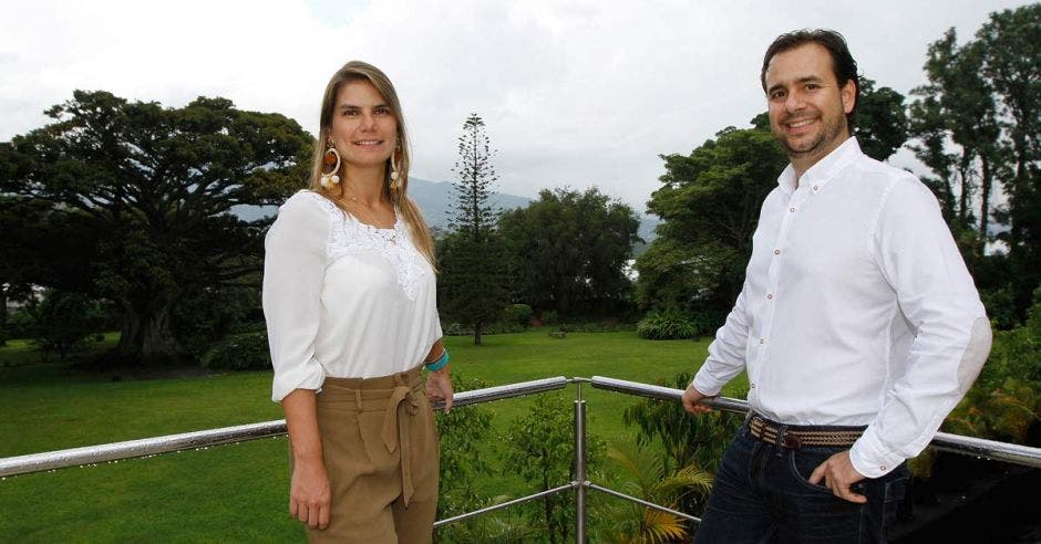 Los dos gerentes vestidos de camisas blancas y pantolón negro color negro en el hombre y café para la mujer y en el fondo una especie de  bosque