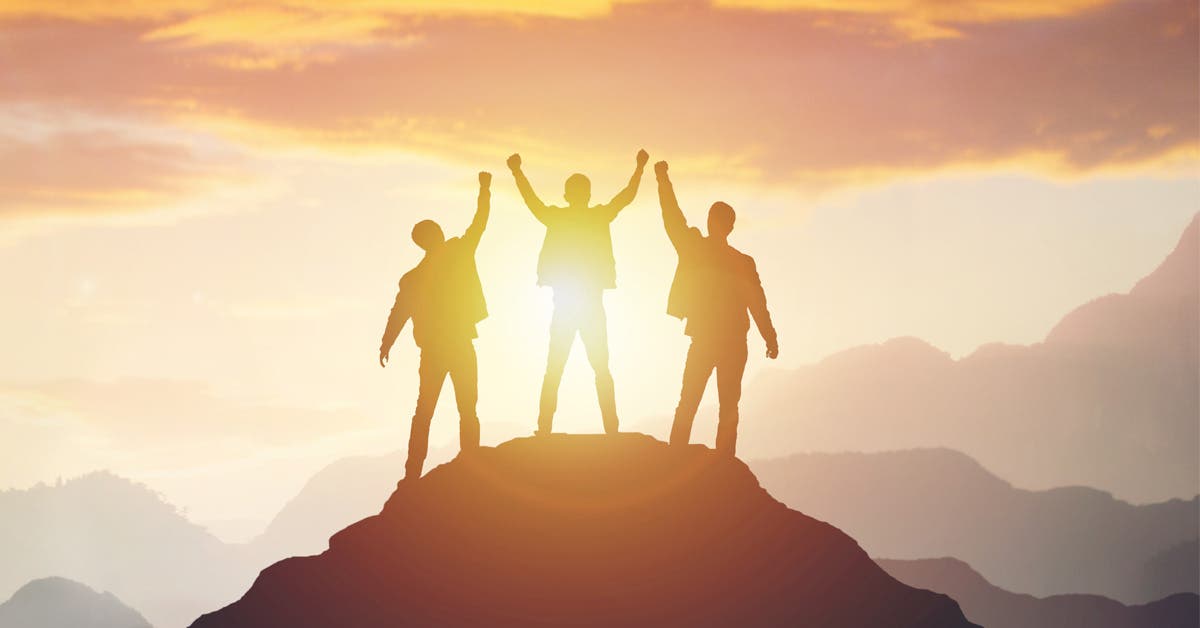 Tres amigos celebran en la cima de una montaña