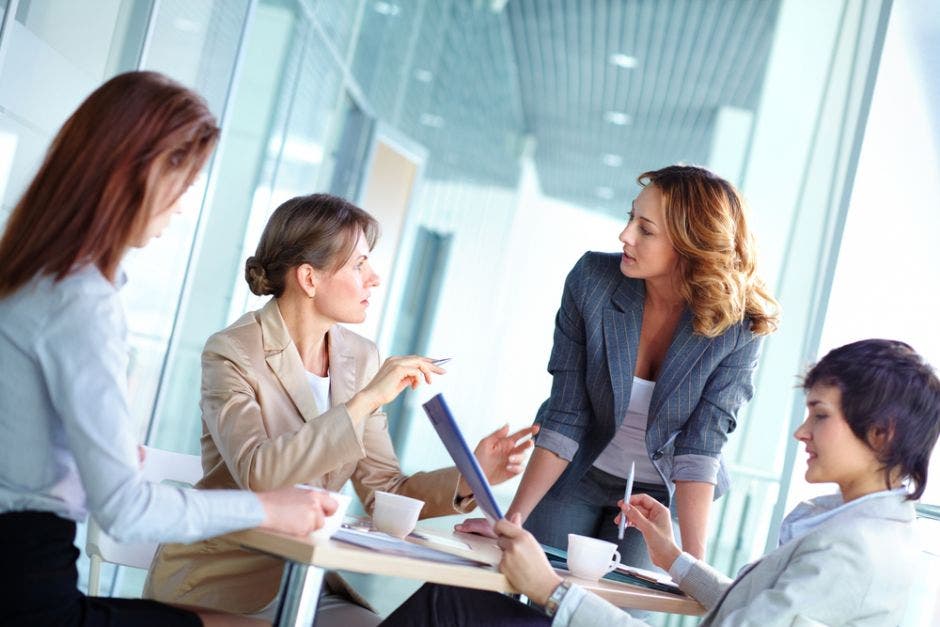 grupo de cuatro mujeres  unidas trabajando en una oficina