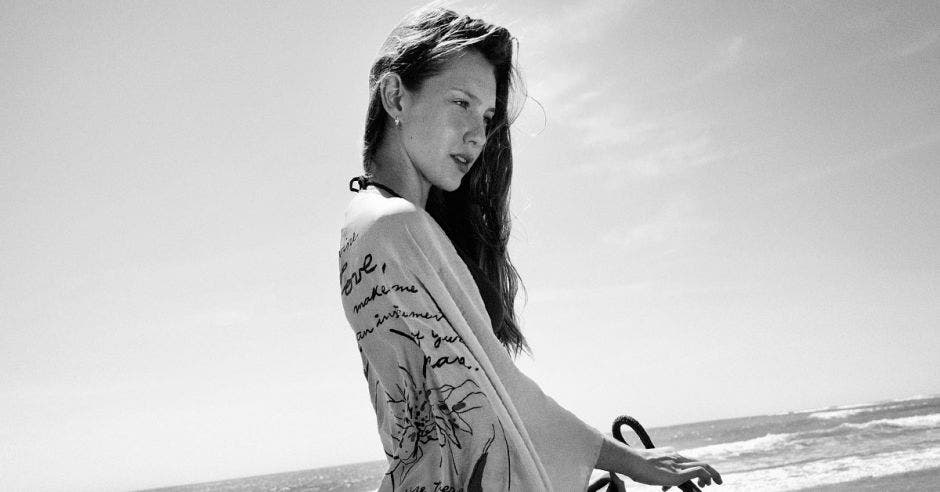 Una mujer en la playa con una blusa manga larga holgada, foto en blanco y negro