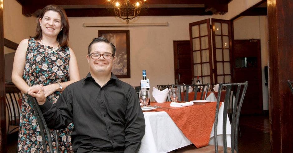 La gerente del restaurante junto a su hijo con síndrome de down, sonrientes, en el restaurante