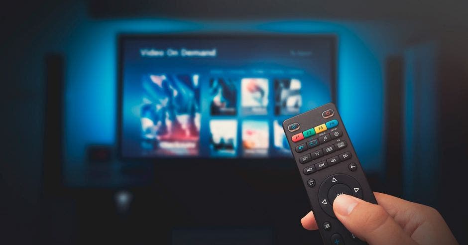 Mano cambiando opciones de programas en la televisión con el control