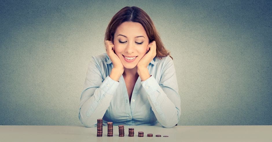 mujer feliz por ver sus grupitos de monedas crecer