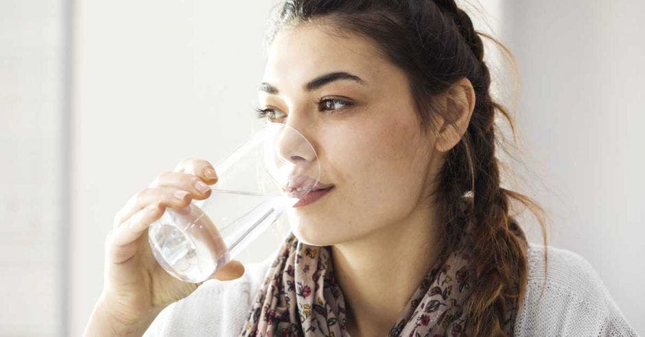 Una mujer morena joven toma agua de un vaso