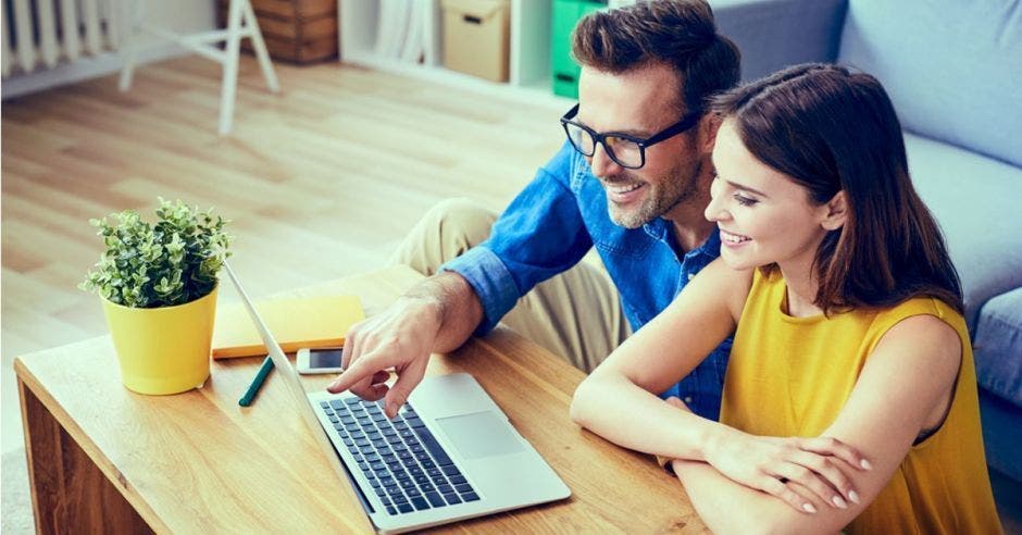 pareja feliz viendo y señalando una computadora