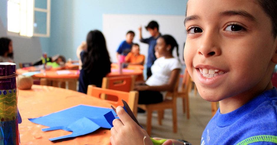 Un niño en una clase sonriente mientras hace unos recortes