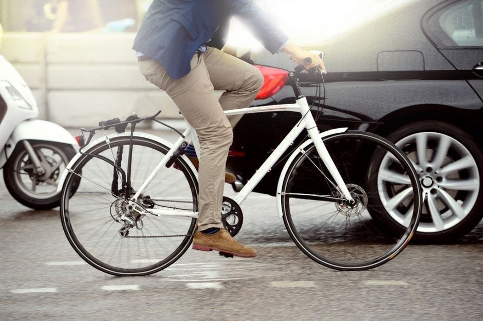 persona en bicicleta y un auto de fondo