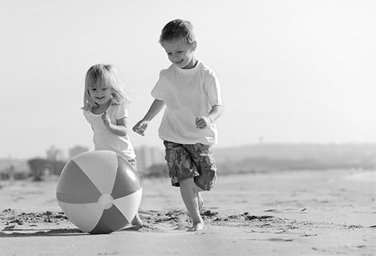 Una pareja de niños juega con una pelota en la playa