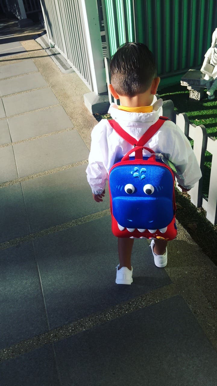Niño caminando con una mochila de dinosaurio