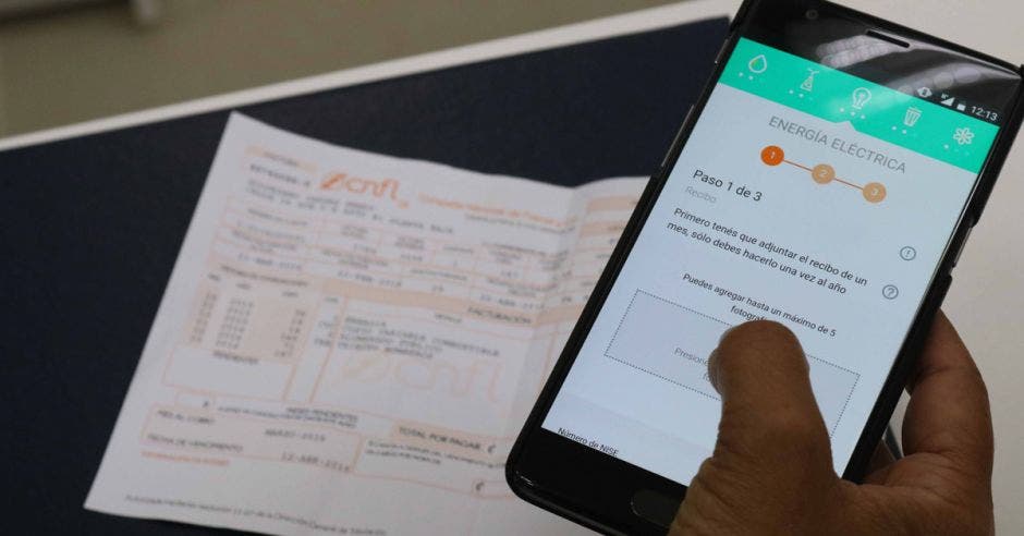 recibo de la CNFL de fondo mientras una persona registra los datos en la aplicación Hogar Azul