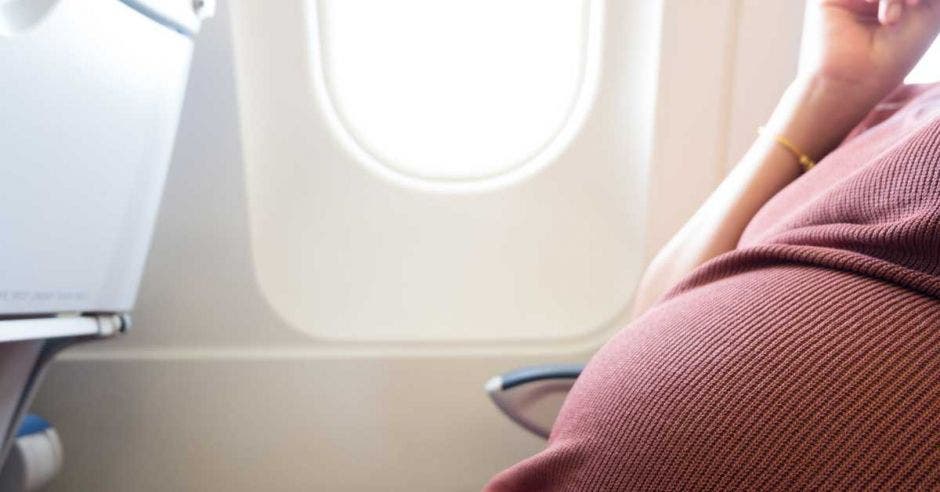 Una mujer embarazada viajando en avión