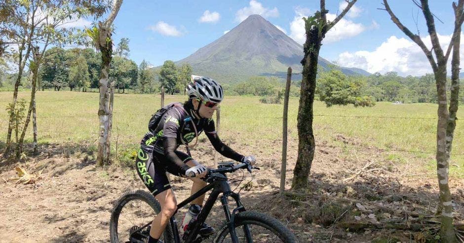 Uno de los participantes de la competencia pedaleando en su bicicleta con el volcán Arenal de fondo