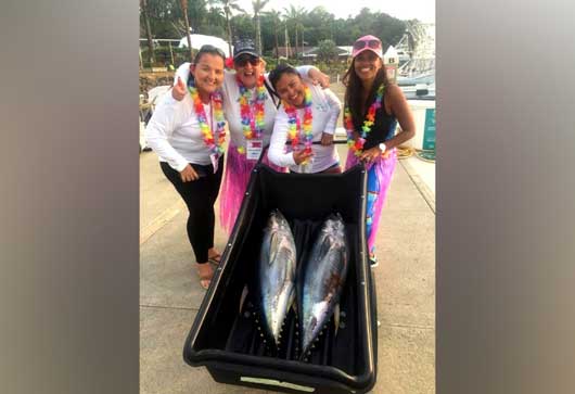 Un grupo de cuatro mujeres posa con un par de peces vela