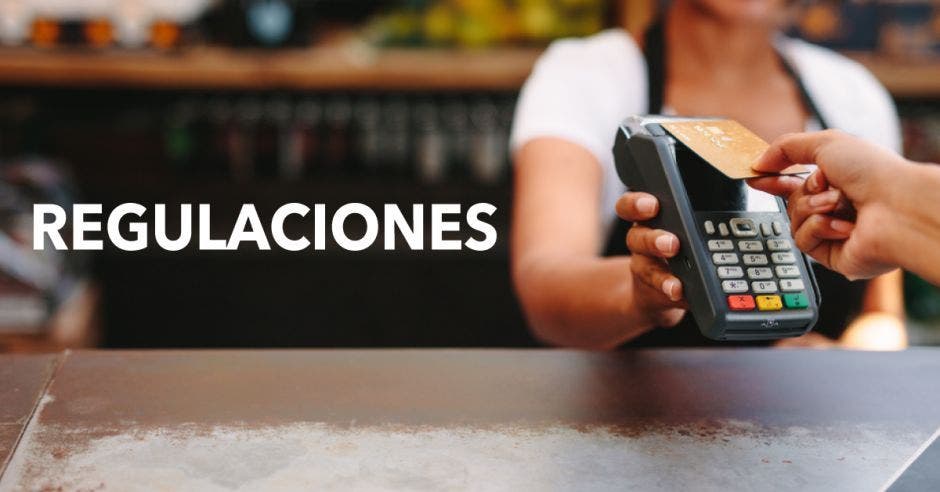 Una persona paga en un comercio con una tarjeta de manera contactless en un datáfono