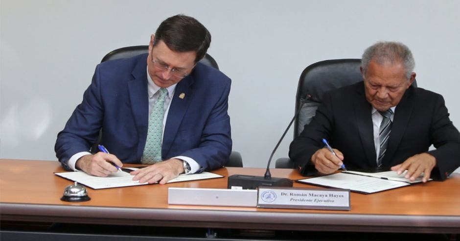 Román Macaya, el presidente de la Caja firmando el convenio con Israel Hernández, rector de Unibe