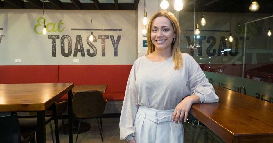 Una mujer morena y de pelo castaño posa junto al mostrador de un restaurante