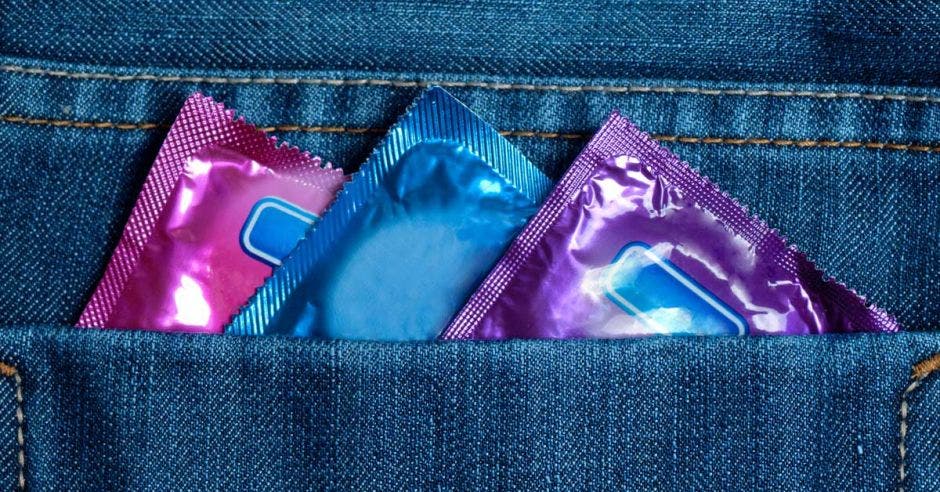 Tres condones multicolor en la bolsa de atrás de un pantalón
