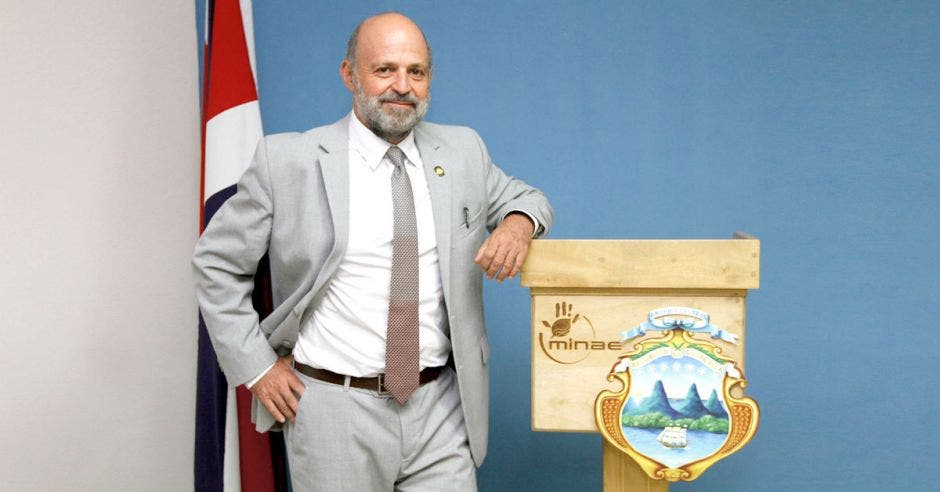 Ministro Carlos Manuel Rodr[iguez posa junto a un atril que tiene el escudo de Costa Rica