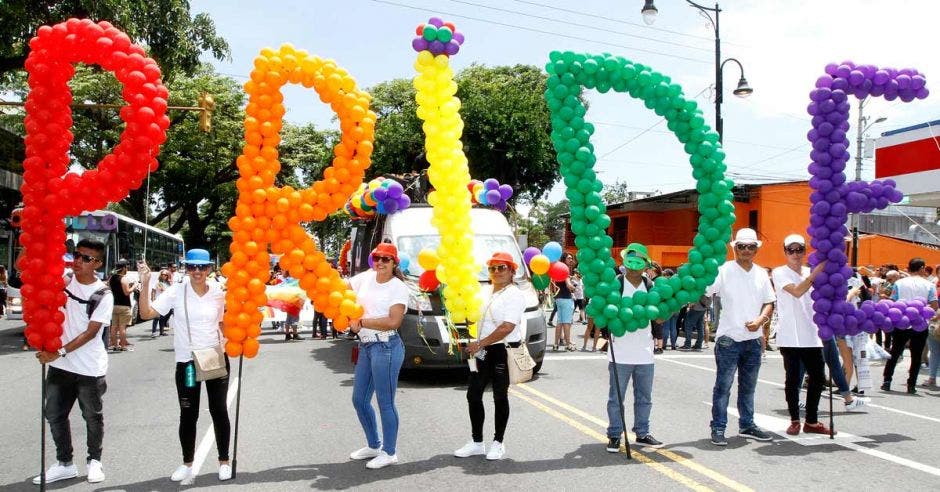 Personas sosteniendo globos formando la palabra Pride