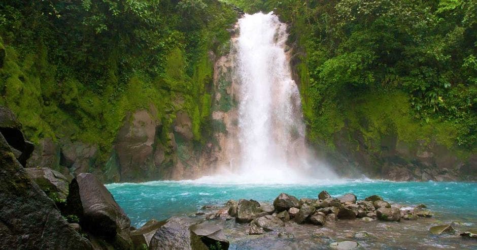 Una catarata cae sobra una poza celeste