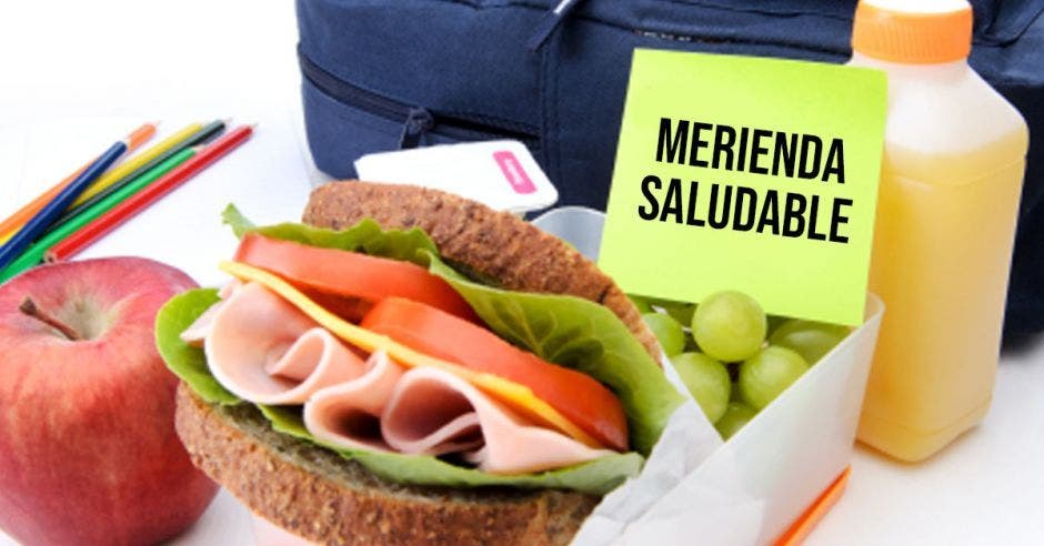 merienda de un sandwich y unas frutas con el letrero de merienda saludable