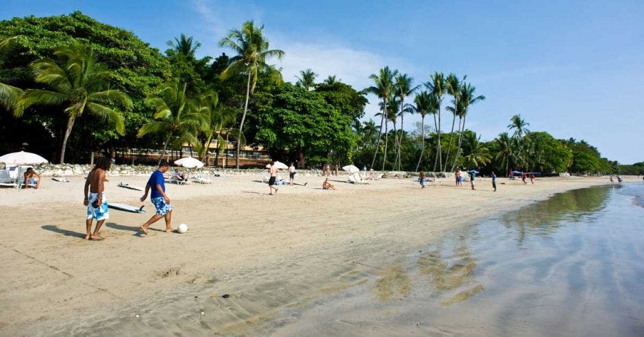 Varias personas juegan fútbol en la playa