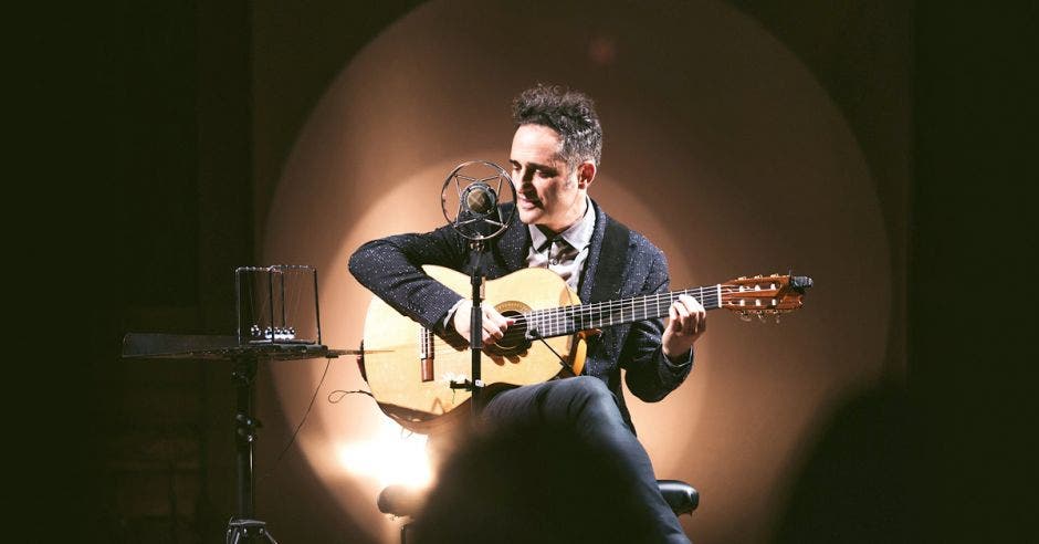 Un músico toca su guitarra frente a un micrófono