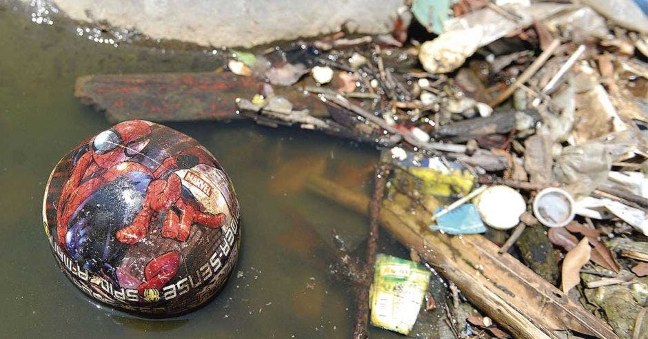 Una balón de plástico flota sobre un río color cafe