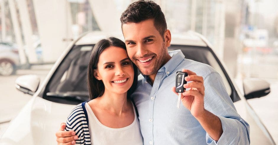 Pareja feliz con un carro de fondo