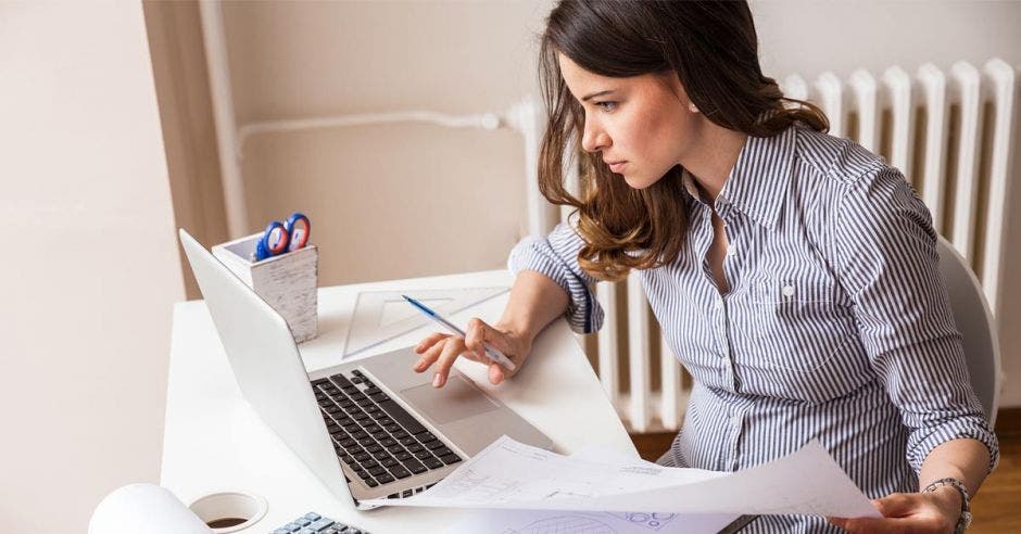 Mujer revisando facturas en una computadora