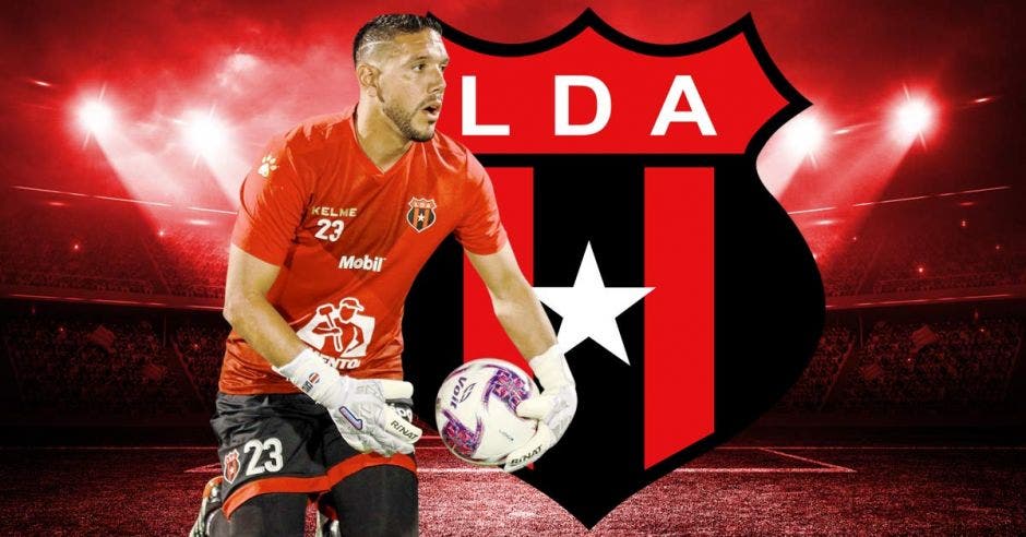 Moreira recoge un balón vestido con el uniforme de Alajuelense y con el escudo de la Liga de fondo