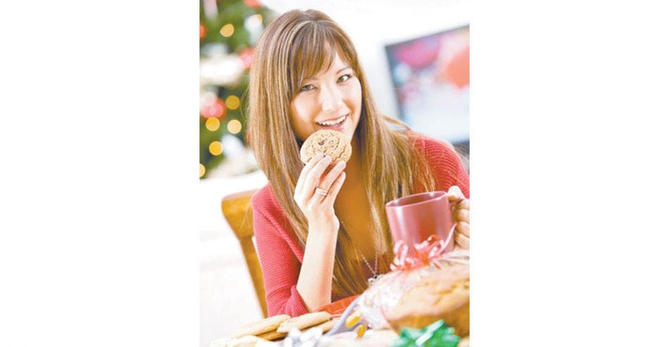 Mujer sosteniendo un vaso y en la otra mano una galleta