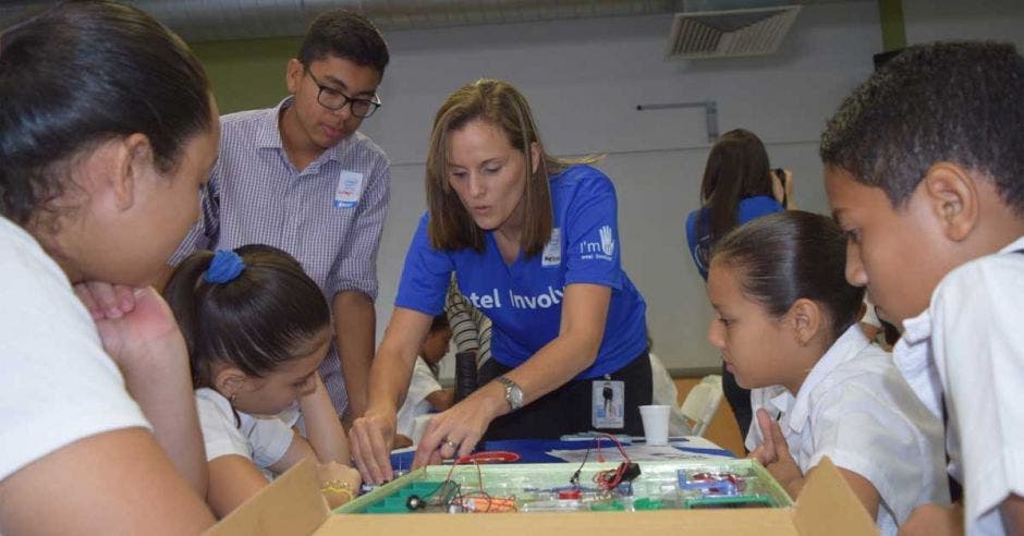 Una mujer con blusa azul imparte un taller de robótica