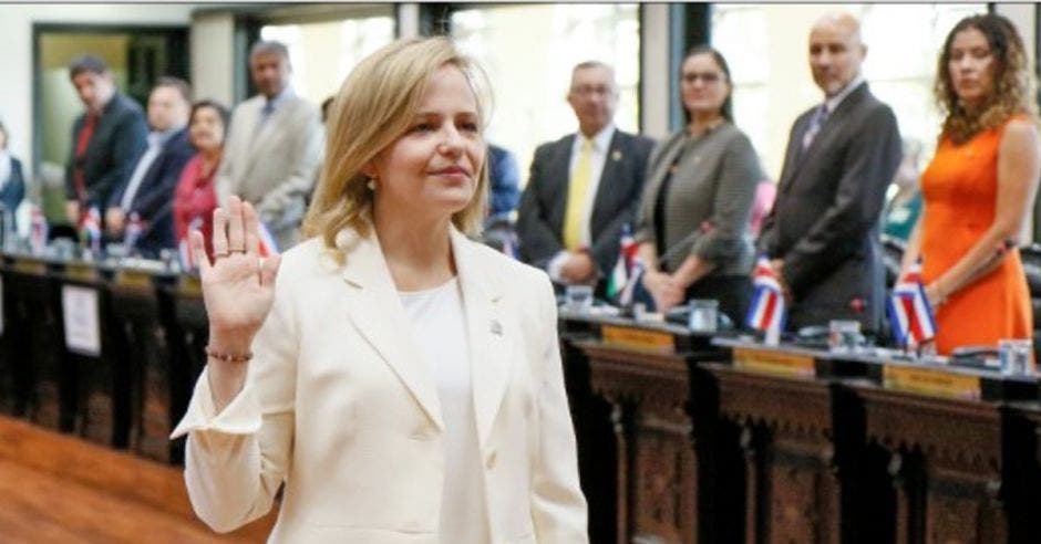 Catalina Crespo con un traje blanco levantando su mano izquierda en señal de juramento