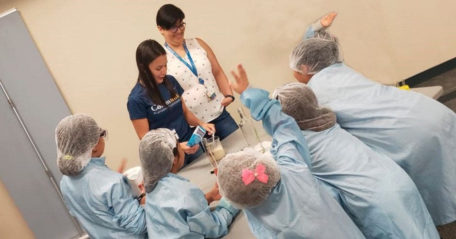 Dos mujeres adultas atienden un grupo de niñas en un laboratorio