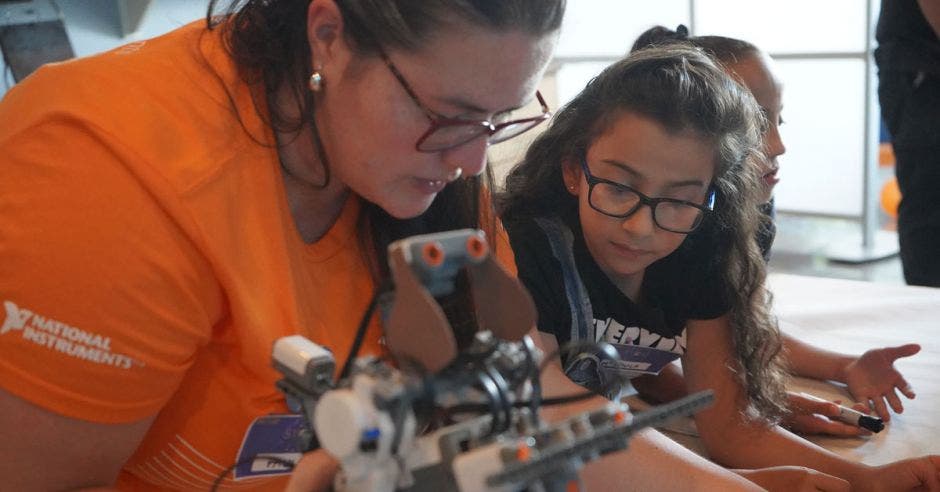 Una mujer voluntaria enseñándole a una niña sobre robótica