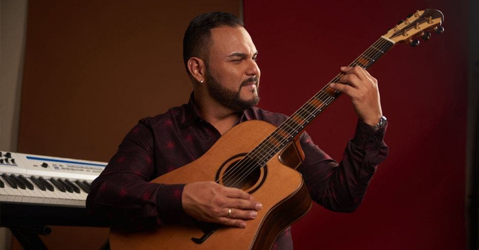 El productor y cantante nacional, tocando la guitarra con un piano de fondo