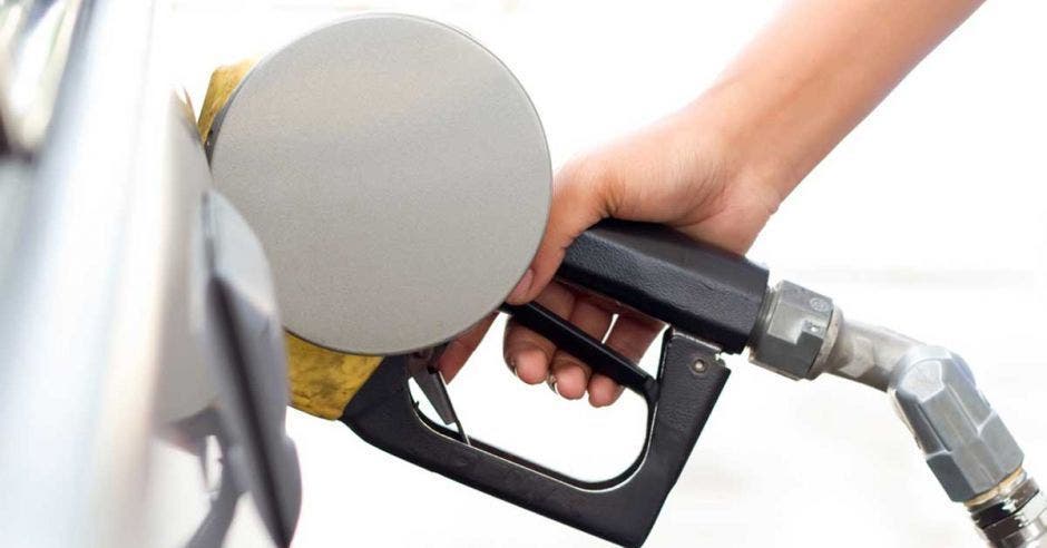 Una pistola echando gasolina en un tanque de gasolina de un carro blanco